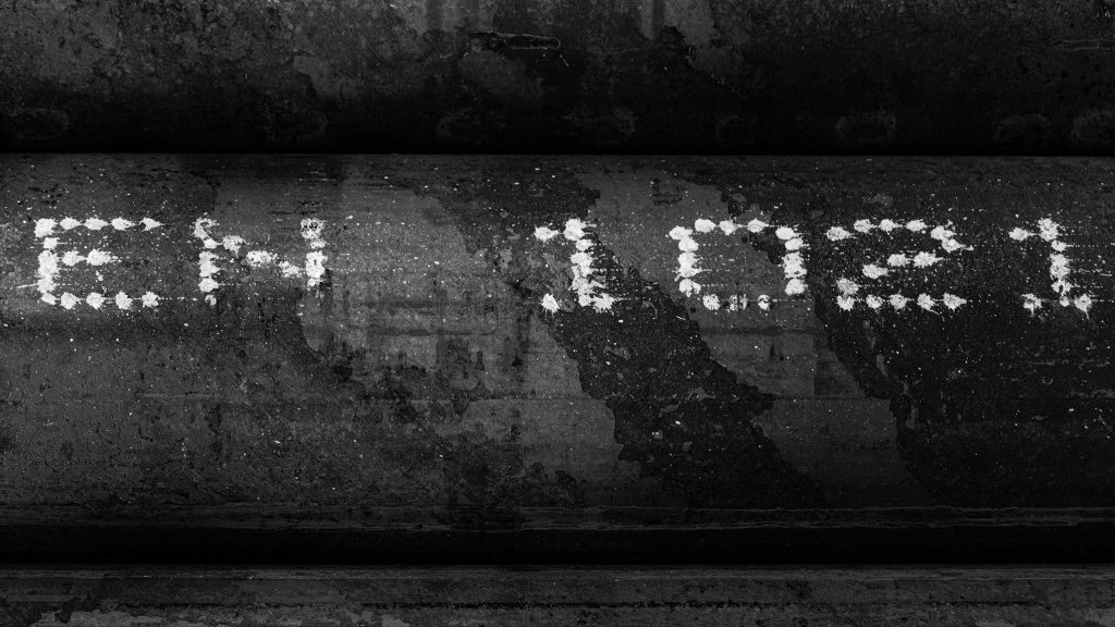 Nahaufnahme einer Metalloberfläche mit der Aufschrift EN 1021 in weisser Farbe.