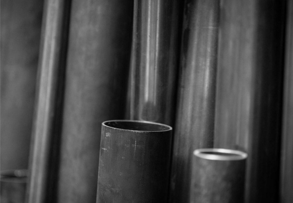 Nahaufnahme von mehreren stehenden Metallrohren in verschiedenen Grössen, schwarz-weiss.